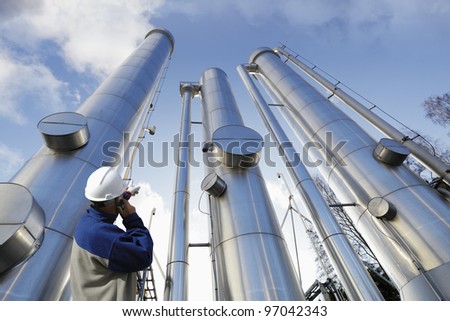 engineer, worker, pointing at giant gas and oil pipes