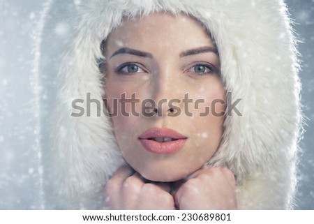 Portrait of a young woman wearing a fur cap. Snowy winter day