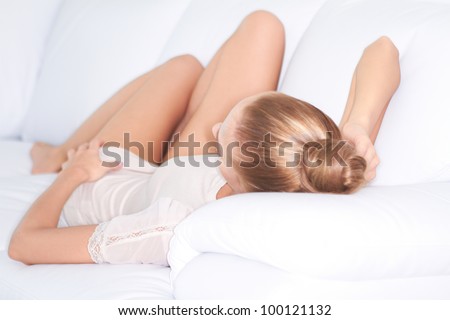 View from the top of her head of a blonde woman having a relaxing day reclining on a white sofa