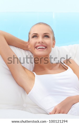 Adorable woman smiling broadly and looking off camera while seated on a white couch