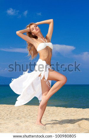 Sensual woman with scarf around her waist posing at the beach