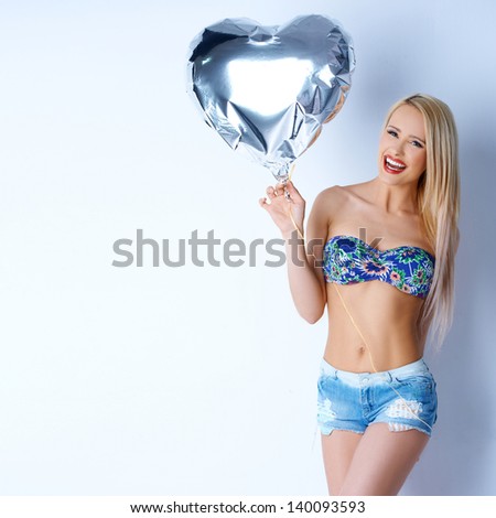 Happy sexy blond girl in short jeans holding silver balloon