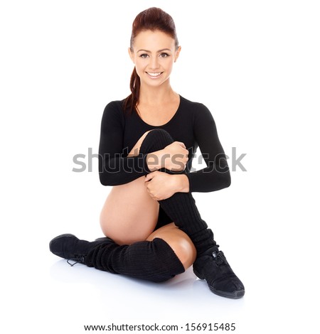 Smiling friendly supple woman with a beautiful smile sitting on the floor with her legs and arms intertwined during training exercises to maintain her fitness and increase mobility  on white