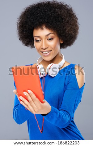 Beautiful young Afro-American woman selecting a tune on her storage device with a smile of anticipation