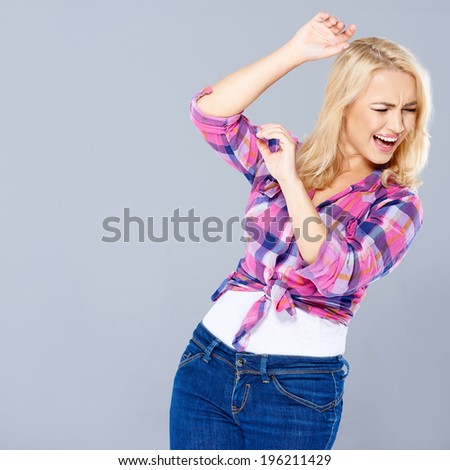 Attractive trendy young woman rearing back from physical abuse raising her hands to shield herself while looking away in anguish  three quarter on grey with copyspace