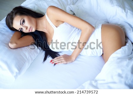 Sexy beautiful young woman lying awake in bed in her sleepwear as she struggles to get to sleep due to insomnia