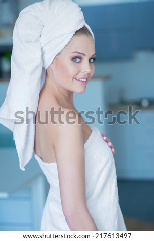 Smiling Young Woman Wearing White Bath Towel Looking Over Shoulder at Camera