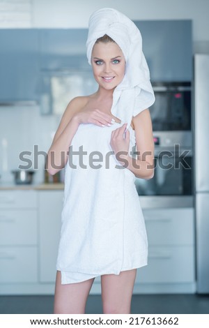 Three Quarter Length Portrait of Smiling Young Woman Wearing Bath Towel in Kitchen