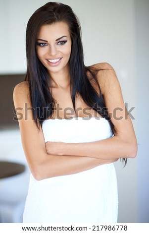 Smiling Woman with Long Dark Hair and Arms Crossed Wearing White Bath Towel and Looking Down