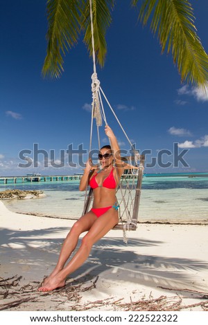Pretty Sexy Woman in Red Bikini with Shades Playing on Swing at the Beach
