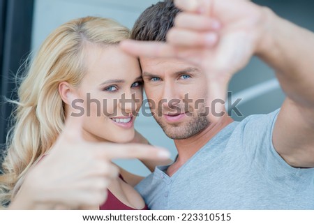 Close up Romantic Couple in Hand Frame Sign. Looking at Camera.