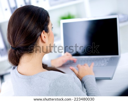 Back view of woman on her laptop in the office