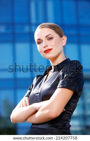 Confident White Office Girl with Crossed Arms in Sexy Black Blouse Looking at Camera. Isolated on Huge Building Glass Walls.