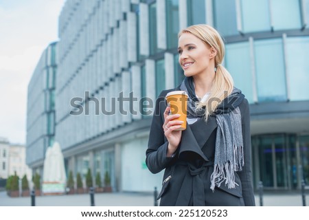 Young Smiling Businesswoman Outside Office Building Holding Cup of Coffee.
