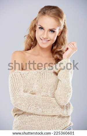 Close up Attractive Smiling Woman in Off Shoulder Knit Long Sleeves Outfit. Isolated on Gray Background.