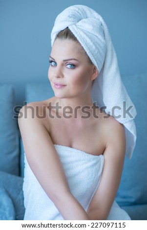 Pretty woman with gorgeous blue eyes with her hair and body wrapped in clean white towels looking sideways at the camera