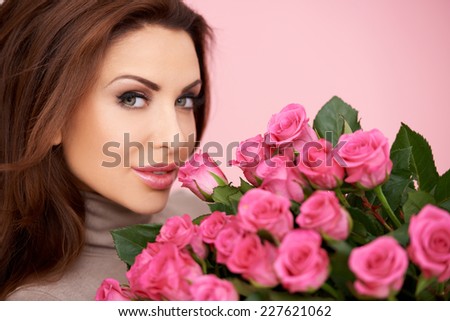 Gorgeous woman with a large bunch of fresh pink roses given her by a loved one for valentines  her birthday or anniversary