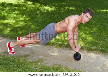 Handsome Athletic Young Man with No Shirt Doing Push up at the Park to Stay Fit While Looking at the Camera.