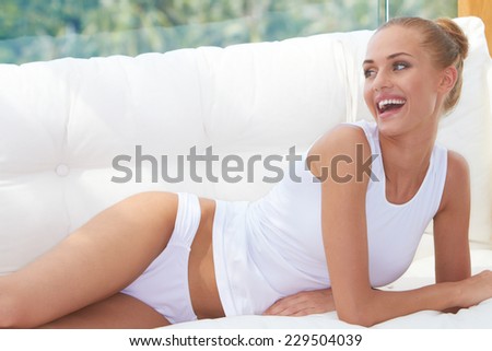 Close up Happy Young Woman Lying on her Side on White Couch Wearing White Underwear.