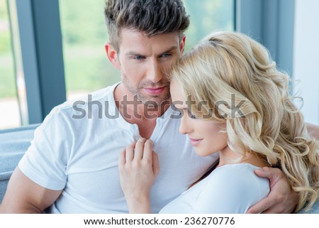 Close up Romantic Young White Couple in Casual White Shirts  Sitting near the Window with Woman Leaning on Man\'s Arm.