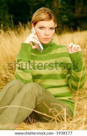 Young business woman using cell phone on golden meadow at mountains outdoors