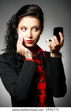 Young Business woman wearing red shirt and black jacket doing make up
