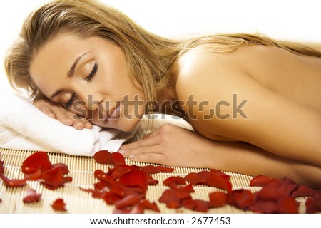 Portrait of Fresh and Beautiful blond woman laying on bamboo mat around flowers and taking spa treatment