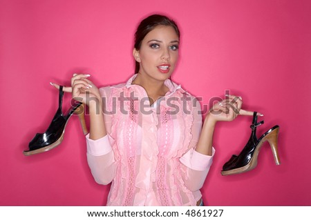 Beautiful and sexy brunette woman isolated on clear colour background holding shoes