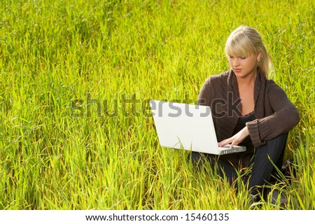 20-25 years old beautiful woman working on laptop computer meadow