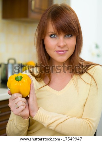 Beautiful woman in kitchen holding yellow pepper