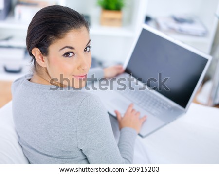 Young woman sitting on couch and working on laptop