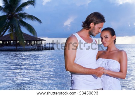Romantic couple standing next to palm tree