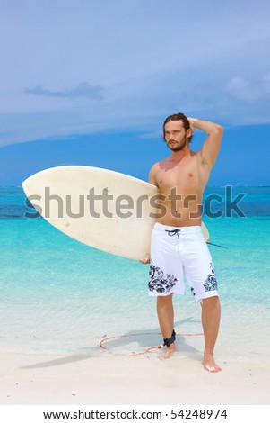 Handsome man standing with surfing board on the beach