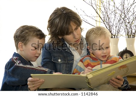 A young mother reading a book for her two son\'s.
