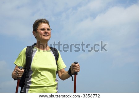 Senior woman doing a Nordic Walk in the sun.