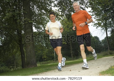 Senior couple running through the woods Senior couple running through the woods