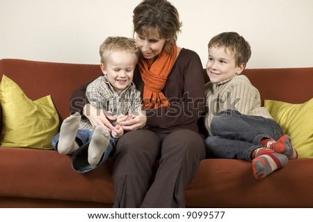 Nice family picture of a mother sitting with her two sons on a couch.