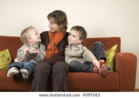 Nice family picture of a mother sitting with her two sons on a couch.