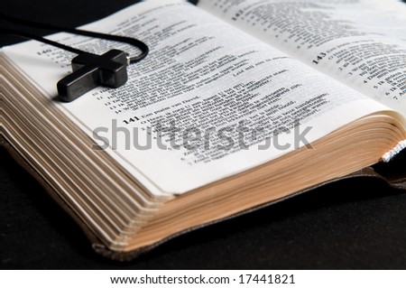 Closeup of Dutch Bible with cross, on black background.