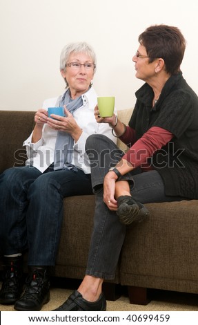 Two senior women drinking coffee, chatting and having a good time together as girl-friends.