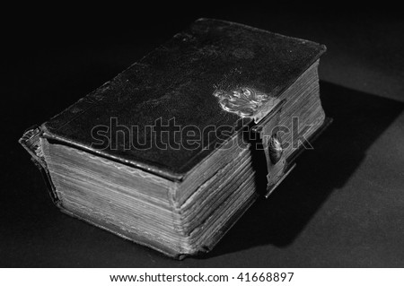 Nice old bible with an old lock on a black background. In black & white.