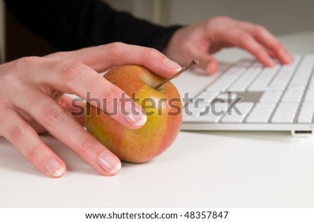 Combination of working and health. Woman is working with an apple as a mouse.