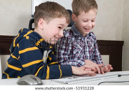 Two friends are having fun while working on a computer.