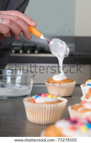 Man is decorating the just baked cupcakes