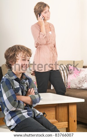 Children are watching tv while mother is calling in the background