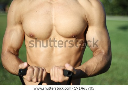 muscular super-high level man pulls rubber bands. outdoors