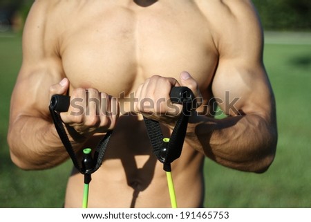 muscular super-high level man pulls rubber bands. outdoors