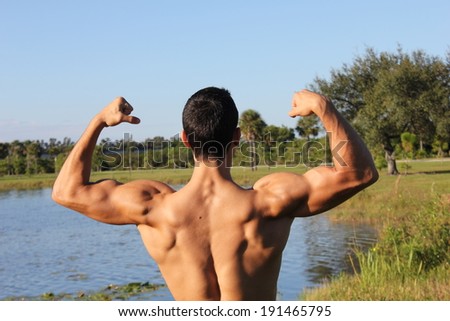 Fit male model showing his biceps and back. outdoors