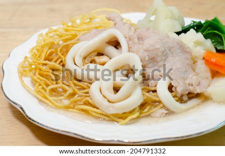 Crispy fried egg noodle with pork and squid and kale soaked in gravy
