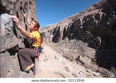 A woman reaches for a climbing hold in Owen\'s River Gorge.